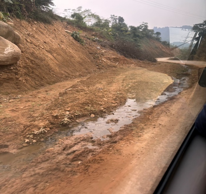 A dirt road with water running through it

Description automatically generated