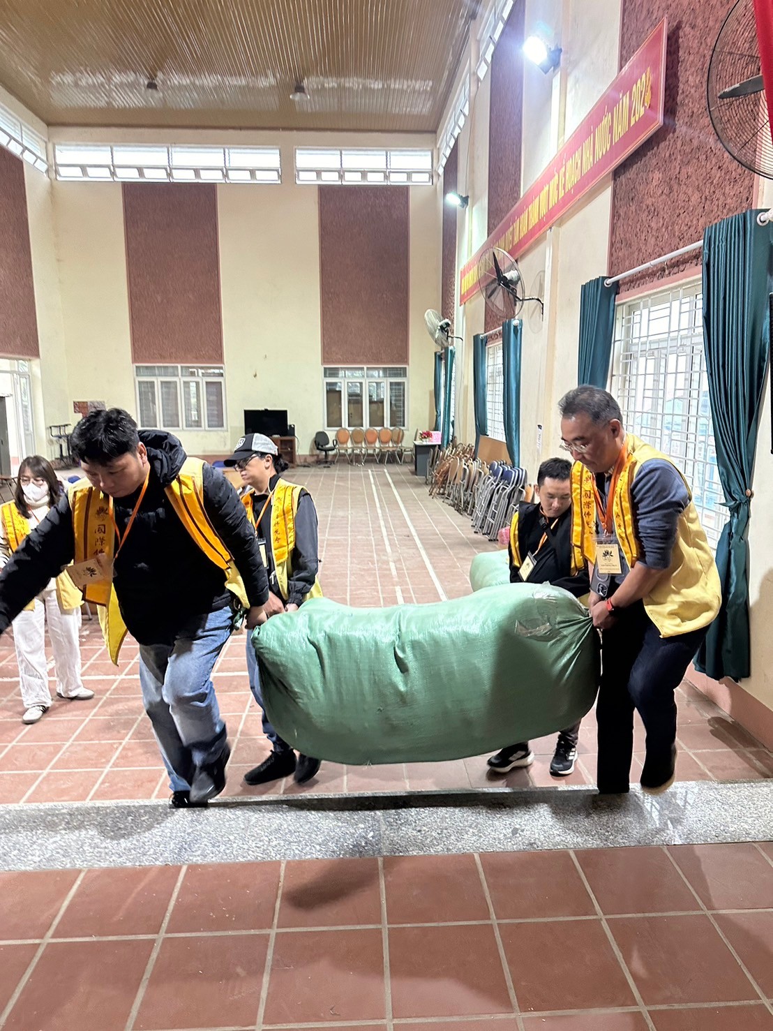 A group of people carrying a green bag

Description automatically generated