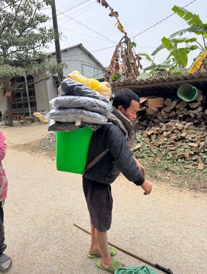 A person carrying a green bucket with clothes on it Description automatically generated